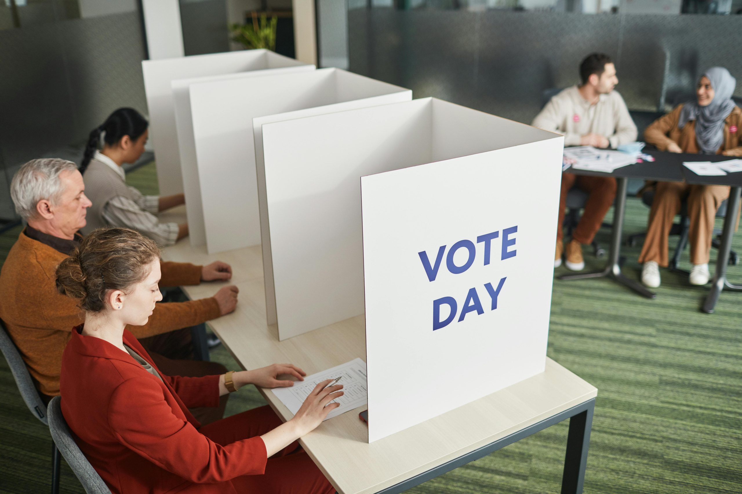 People casting votes in a polling station on election day, emphasizing civic engagement.